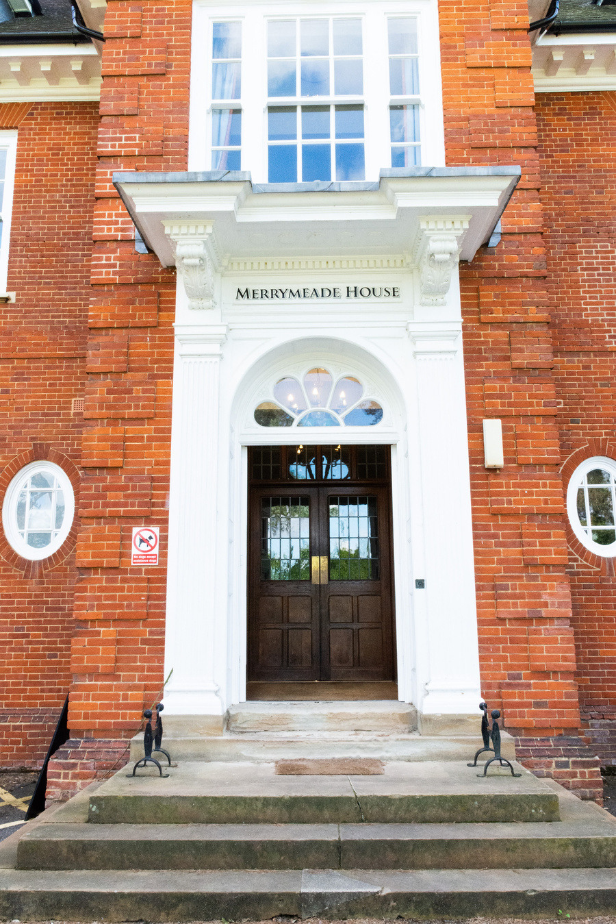 the entrance to Merrymeade House, a red brick building with steps leading up to a decorative porch area