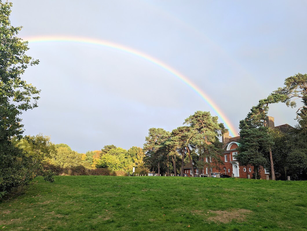 a rainbow in the sky over the front entrance of Merrymeade House